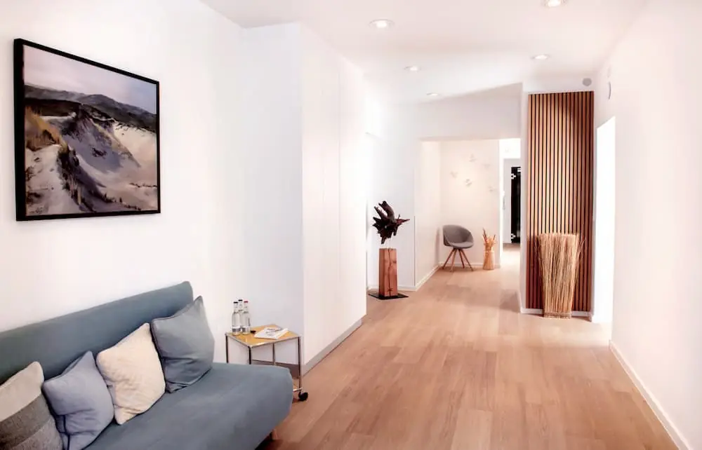 Wartebereich der Zahnarztpraxis Kiel mit Sofa, Kunstdruck und Blick in den Praxisflur